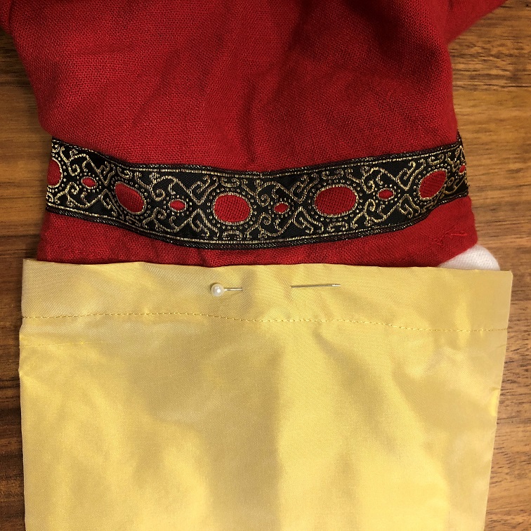 A short-sleeved red dress with a gold silk sleeve pinned on