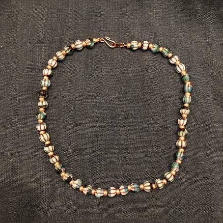 A choker necklace with blue & green melon beads separated by small gold beads