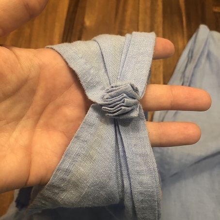 A close up of where the corners of the blue fabric have been gathered and pleated, then sewn together to make a tunic strap